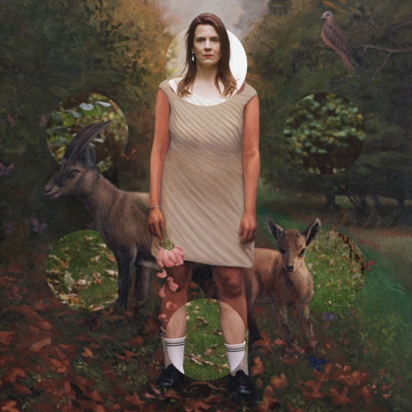 We see a picture with oil painting of Alev standing on a country road through a small forest. Around the painted Alev there are six cricles arranged , two to the sides one top and bottom. Alev is seen in the painting with two mountain goats behind her (one mother one foal). Through the circles we see the same image but as photography. it is a collage of the same image painted and photogrpahed, while the paintng feautres the goats, a hawk on a tree, butterflies and a light pink flower in Alev's hand, some petals falling.